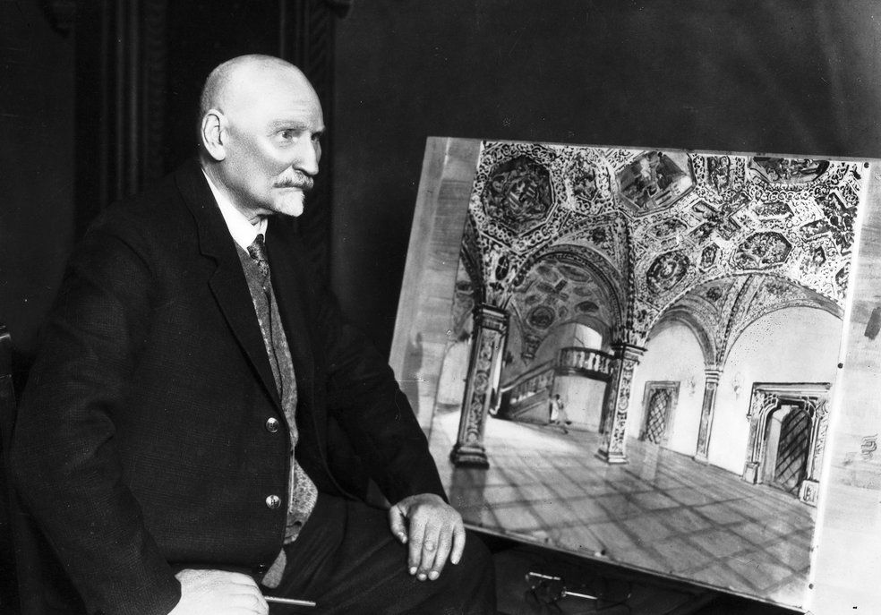 archiwalne czarno białe zdjęcie przestawiające starszego mężczyzne z łysą głową i szpiczastą bródkaubrany w garnitur siedzi bokiem obok niego obraz przedstawiający sale w ratuszu poznańskim