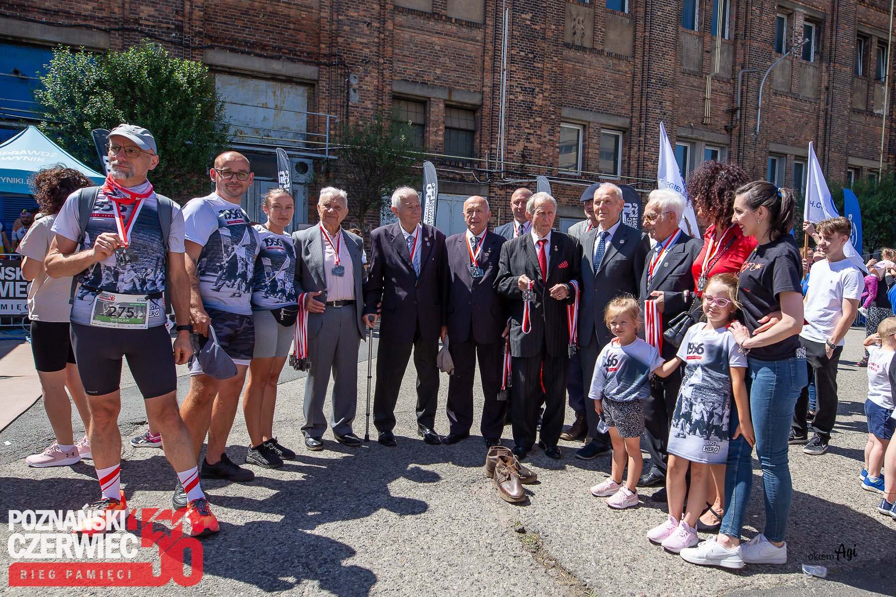 Bieg Czerwca '56 w 2024 roku, fot. Agi Okiem - na pierwszym planie kombatanc Poznańskiego Czerwca '56, którzy otoczeni są uczestnikami biegu w sportowych strojach z medalami. W tle widać budynku Zakładów im. Hipolita Cegielskiego w Poznaniu