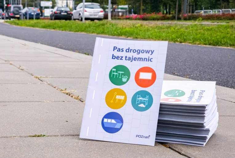broszury ułożone na chodniku, na okładce tytuł "Pas drogowy bez tajemnic"