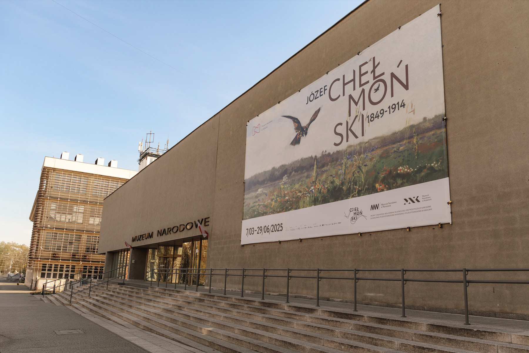 Budynek Muzeum Narodowego, na którym wisi plakat reklamujący wystawę "Józef Chełmoński 1849-1914".