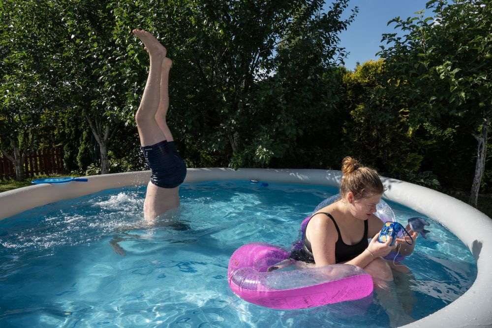 Chłopak w bluzie z napisem "Polska" przysypia na kanapie, mając nogi na deskorolce. Nad nim wisi obraz z Janem Pawłem II.