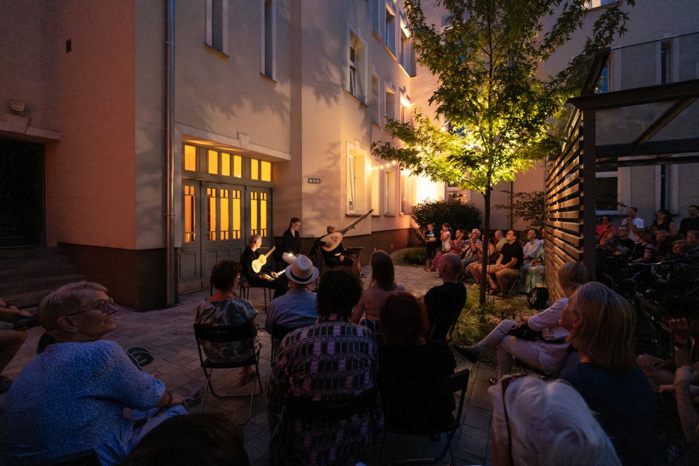 Ciemne podwórze, występuje kolejny zespół, na ścianach budynku wyświetlane są iluminacje i efekty specjalne - wyglądają jak słońce i księżyce w pełni.