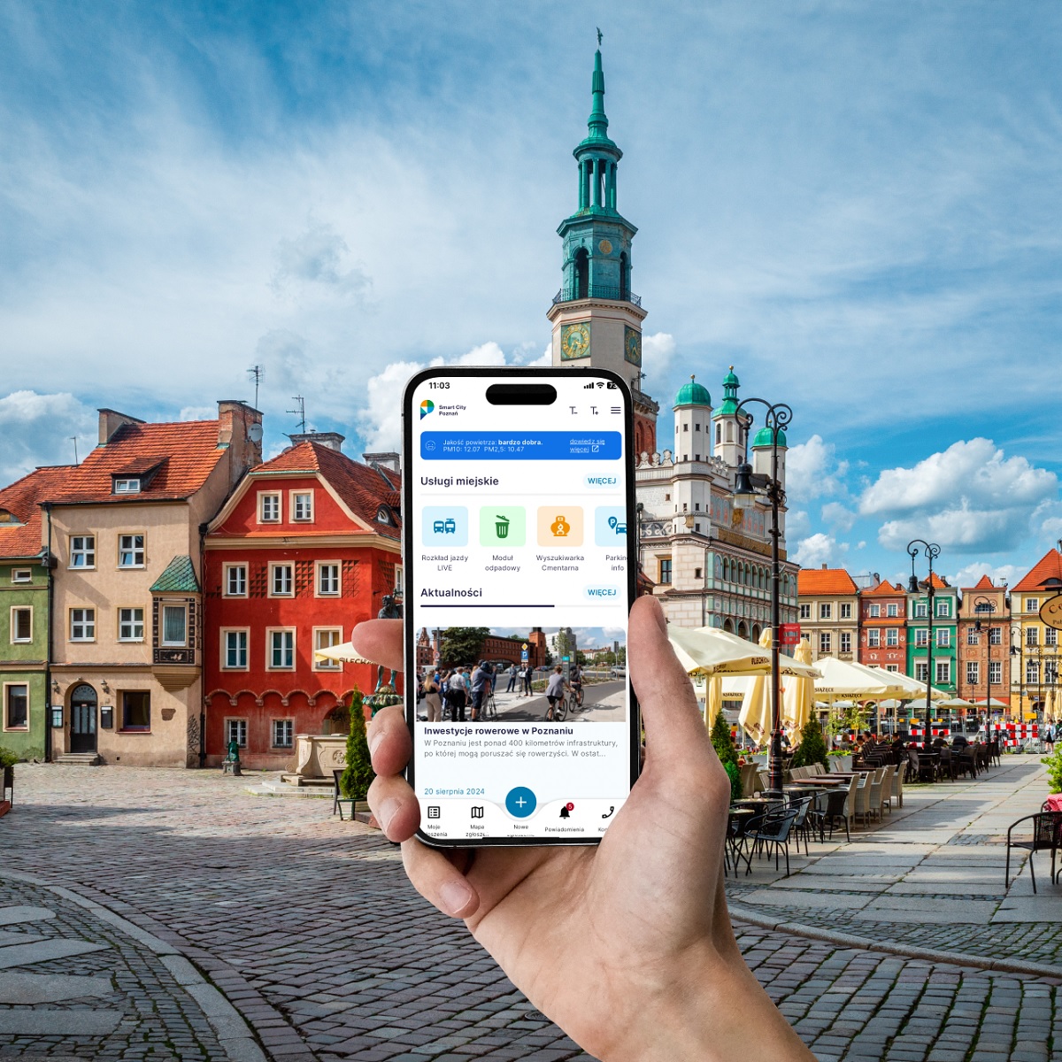 dłoń trzymająca smartfon w tle rynek i ratusz w Poznaniu - grafika artykułu