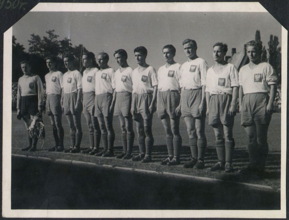 Drużyna piłkarska na boisku, zawodnicy stoją w rzędzie.