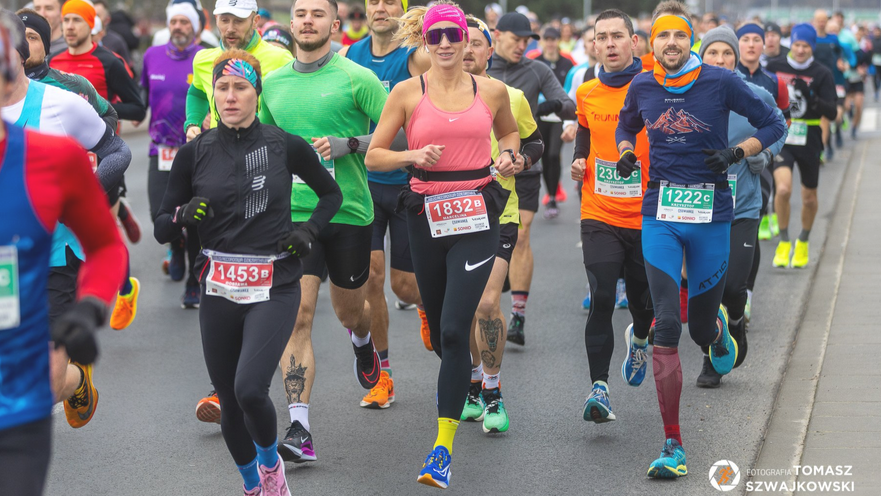 Duża grupa kolorowo ubranych biegaczy na ulicy podczas biegu Recordowa Dziesiątka.