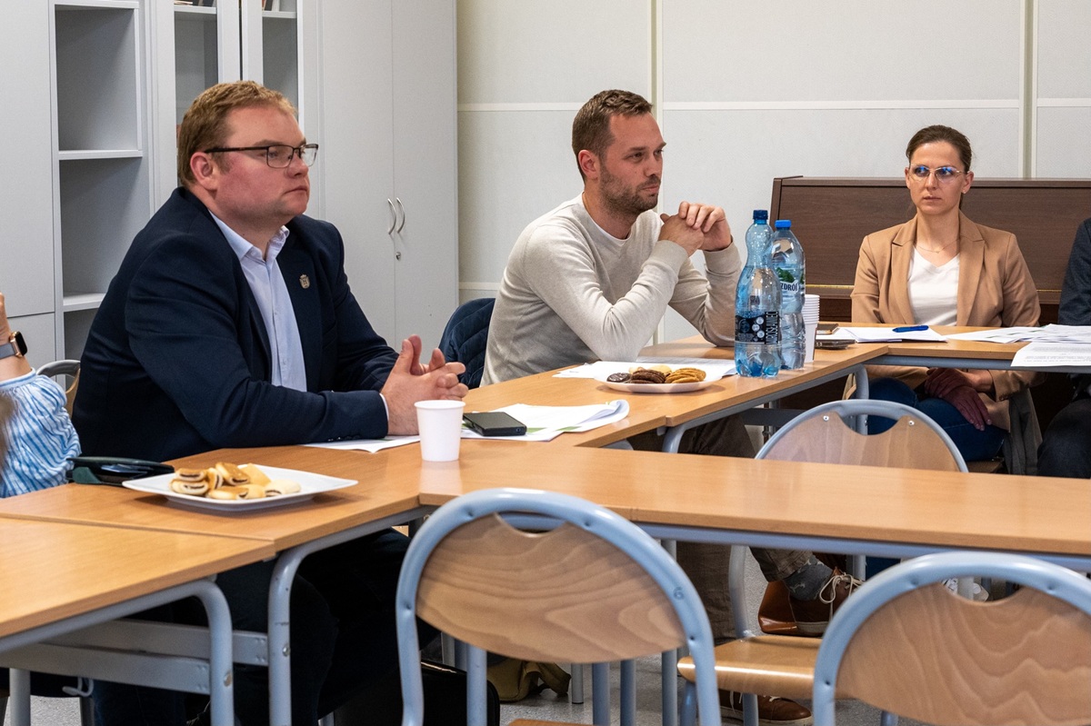 dwóch mężczyzn i kobieta siedzą za stołem w sali konferencyjnej - grafika artykułu