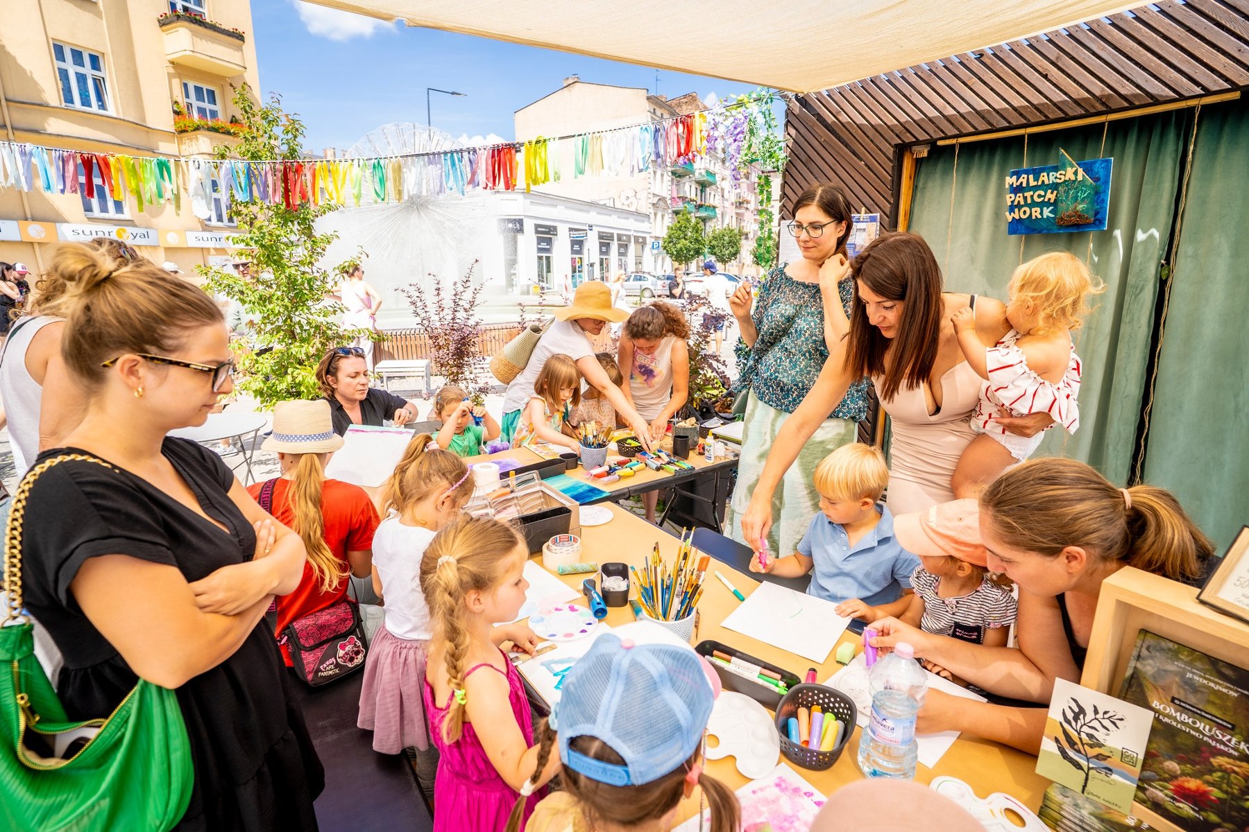 Dzieci i dorośli podczas warsztatów plastycznych przy stole.
