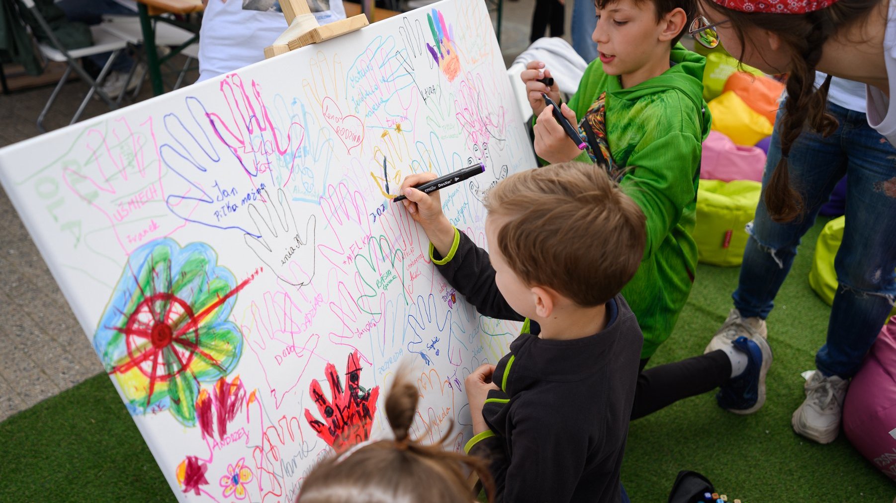 Dzieci malujące kolorami odciśnięte ślady rąk.