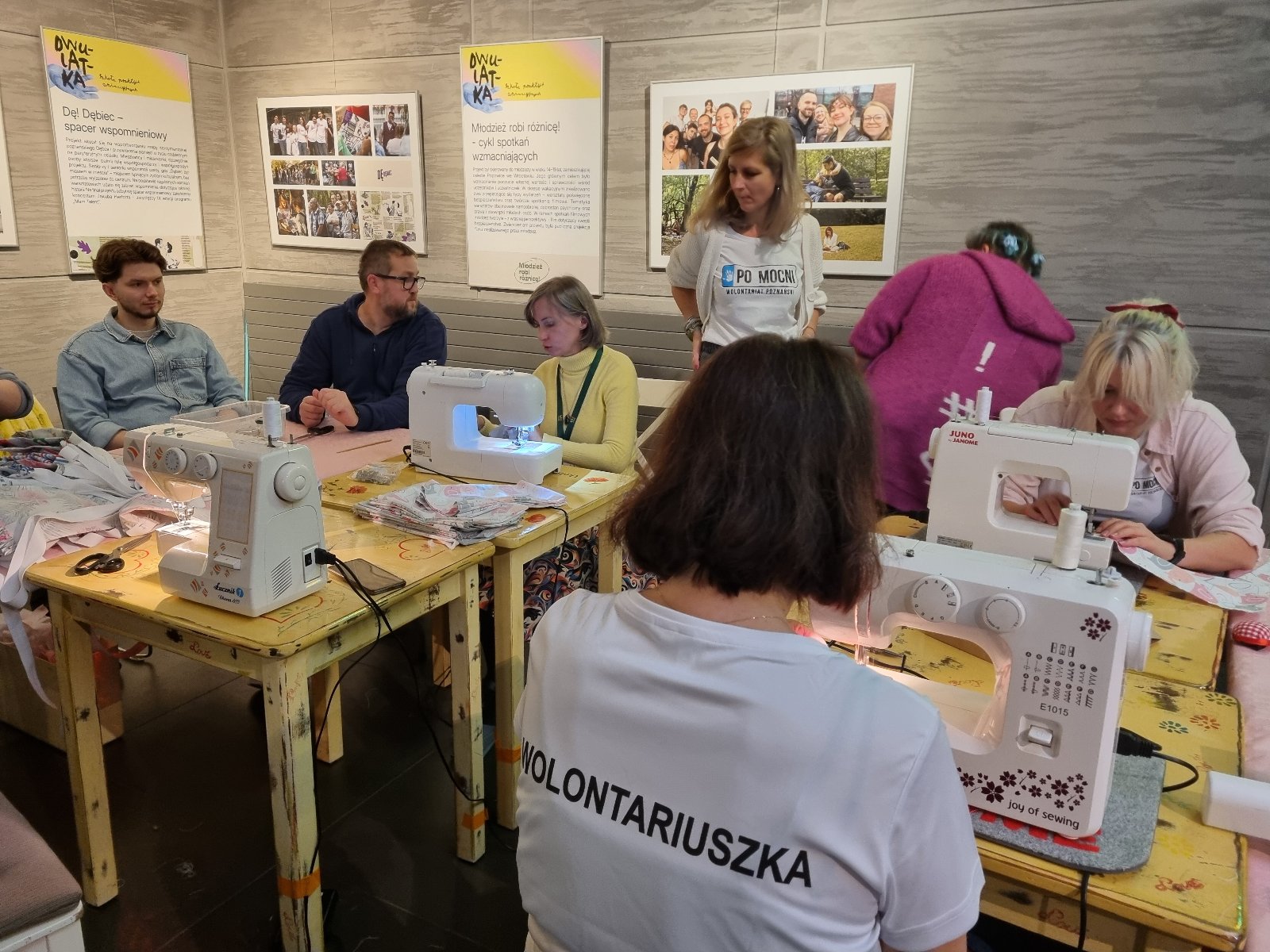 grafika przedstawia parę wolontariuszy, widok na ich plecy