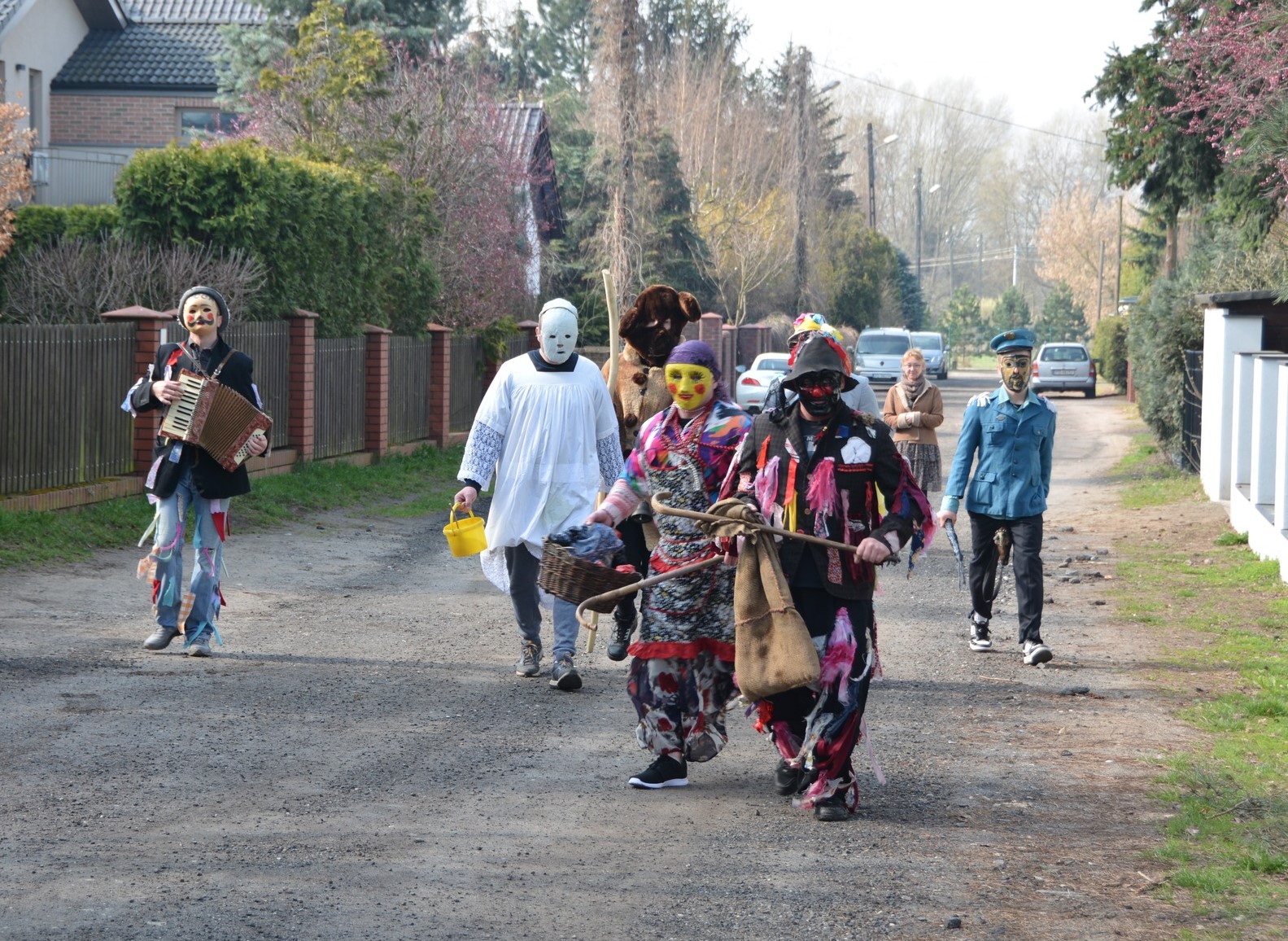 grupa przebierańców na gruntowej drodze biegnącej wzdłuż domów