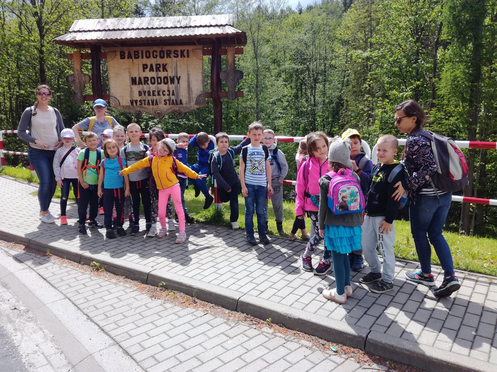 grupa przedszkolaków wraz z opiekunkami przy tablicy Babiogórskiego Parku Narodowego
