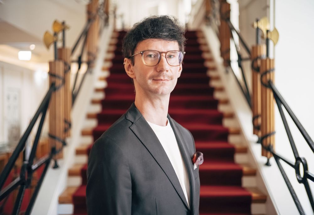 Jakub Dera siedzi na schodach biblioteki, w rękach trzyma zeszyt nut podpisany "Chopin".