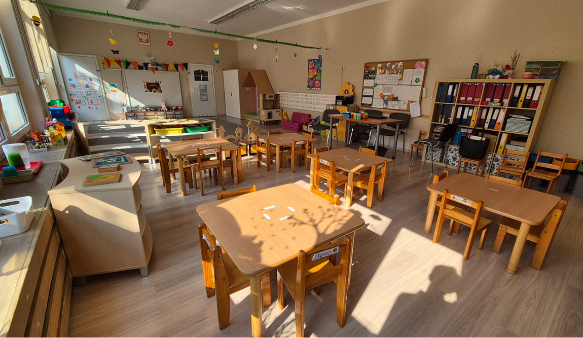 Jedna z sal przedszkola nr 130 w Poznaniu, widoczne stoliki z krzesłami, szafki, tablice, zabawki