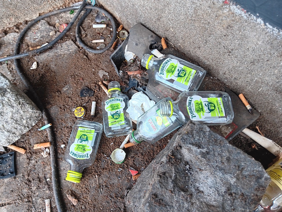 kilka małych butelek po alkoholu pustych pozostawionych na chodniku