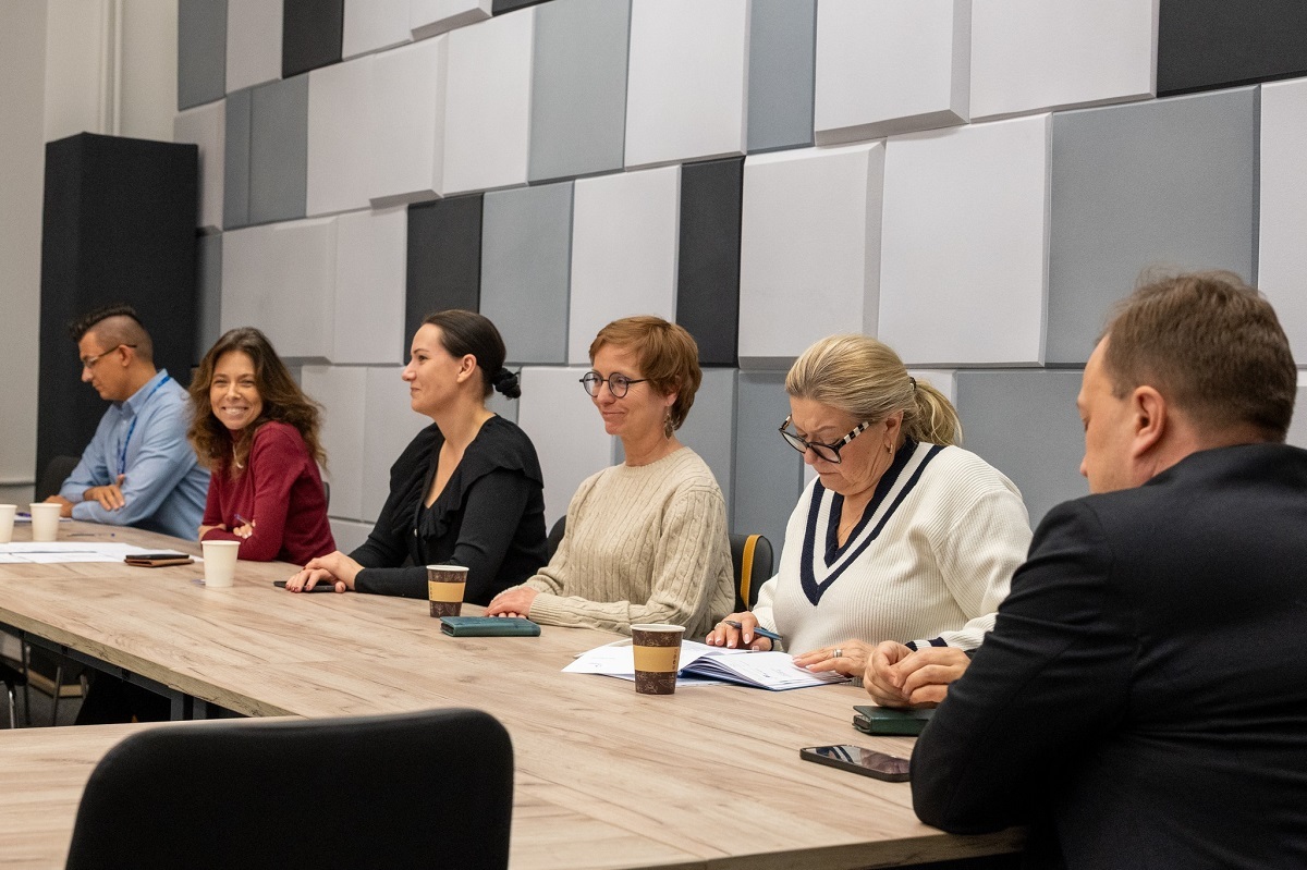 kilkoro osób kobiet i mężczyzn siedzi w sali przy stole konferencyjnym - grafika artykułu