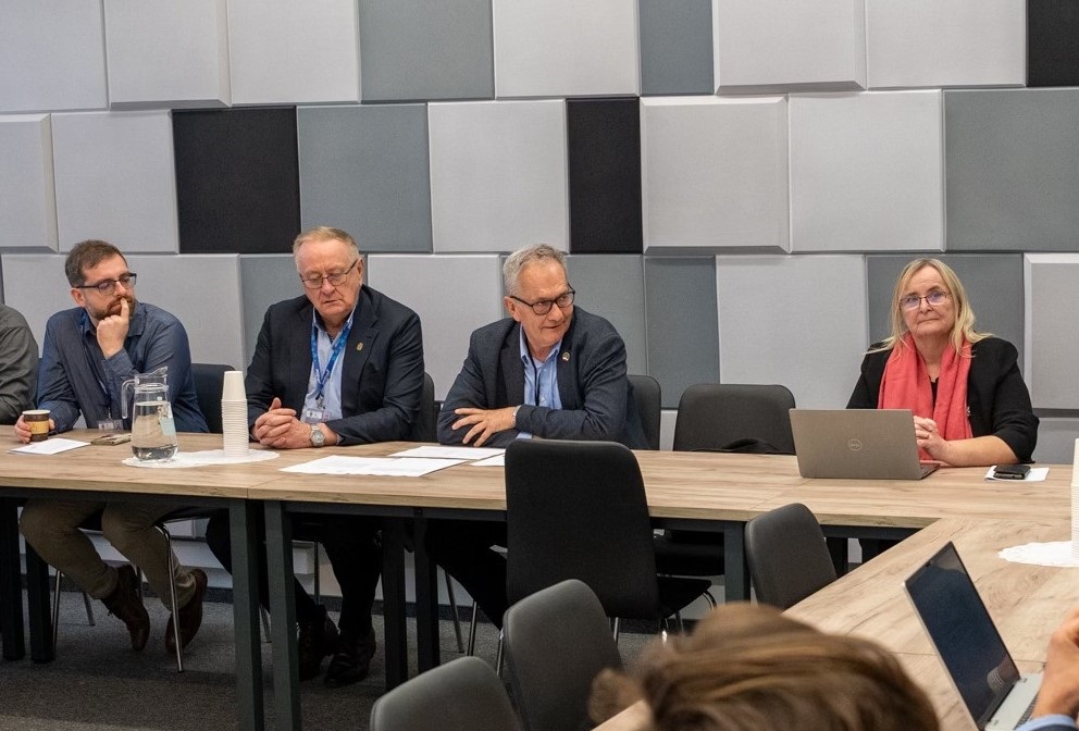 kilkoro osób siedzi za stołem w sali konferencyjnej podczas zebrania - grafika artykułu