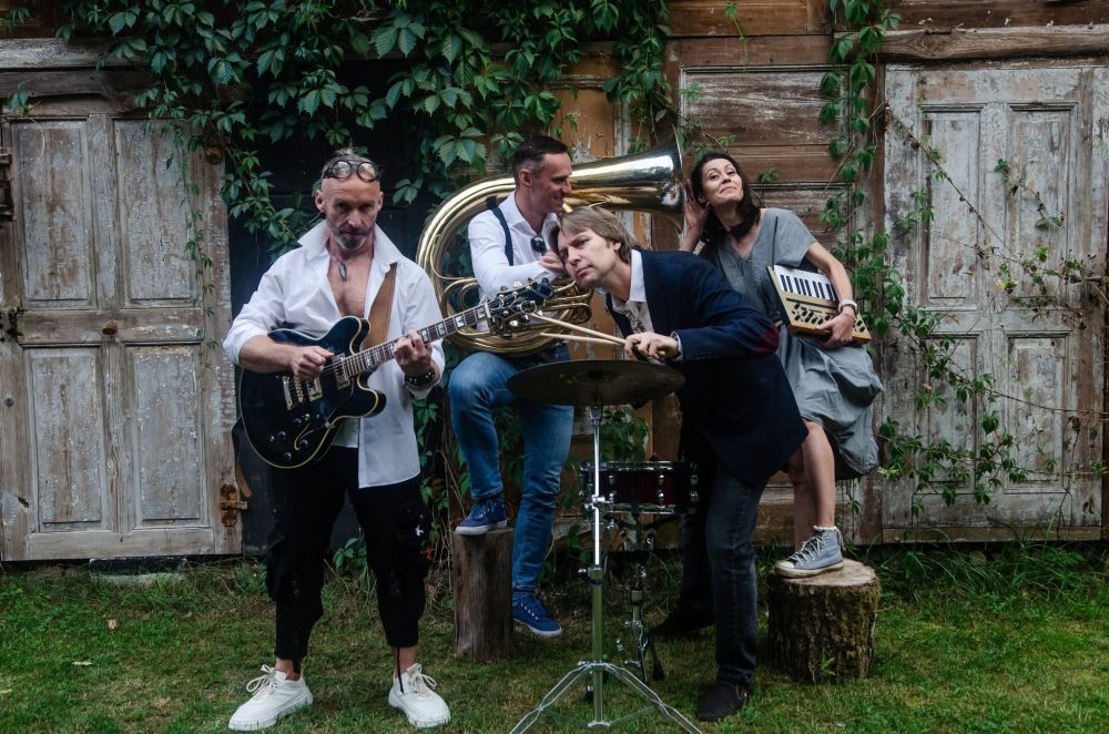 Kobieta i mężczyzna, trzymają instrumenty, ona jasny, on ciemny, przytulają się do siebie z uśmiechem.