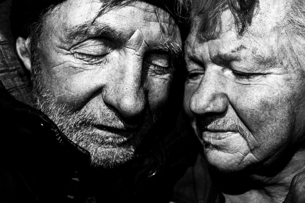 Kobieta przytula do siebie mocno psa, który przykłada bezzębny pyszczek do jej policzka.