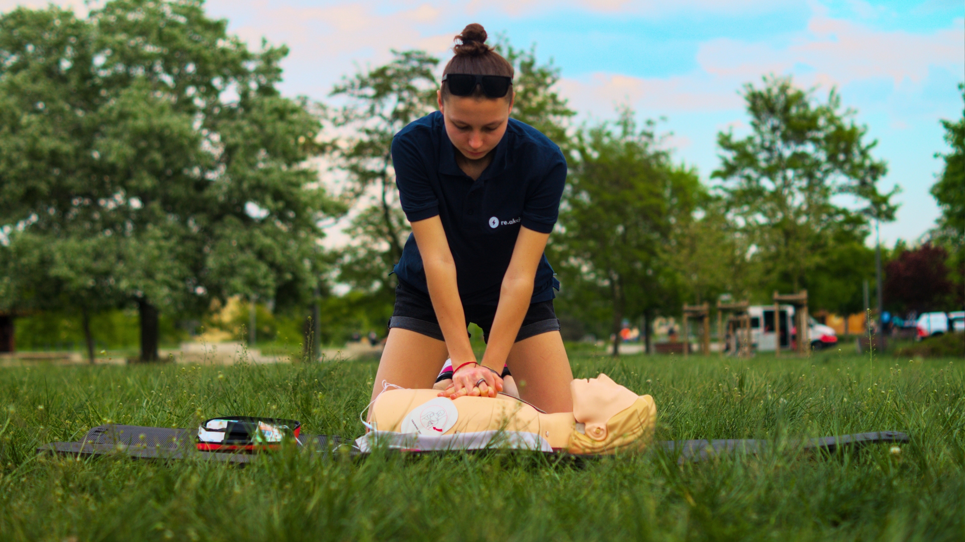 kobieta w trakcie udzielania pierwszej pomocy na fantomie, na trawie