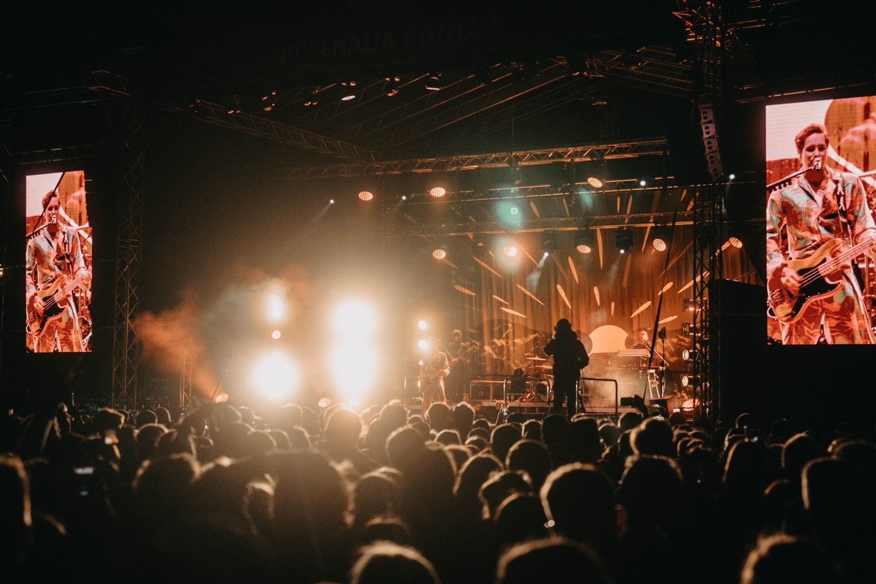 Logo Juwenaliów w Poznaniu z dwoma grafikami głów koziołków, po lewej fioletowy po prawej różowy. Są skierowane w przeciwne strony. W tle fioletowa plama na żółtym tle. Napis "Juwenalia Poznań".