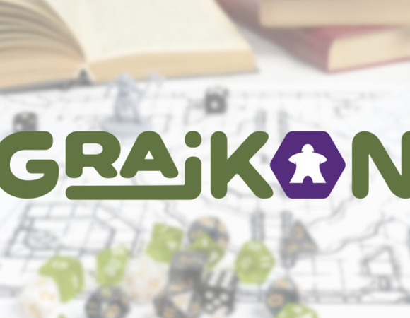 Logo wydarzenia "GRAJKON" na jasnym, rozmytym tle przedstawiającym elementy gier planszowych. Napis wykonany jest grubą, zieloną czcionką, przy czym litera "O" ma kształt fioletowego sześciokąta z białą sylwetką pionka typu meeple w środku. W tle widoczne są zarysy otwartej książki, kości do gry oraz planszy.