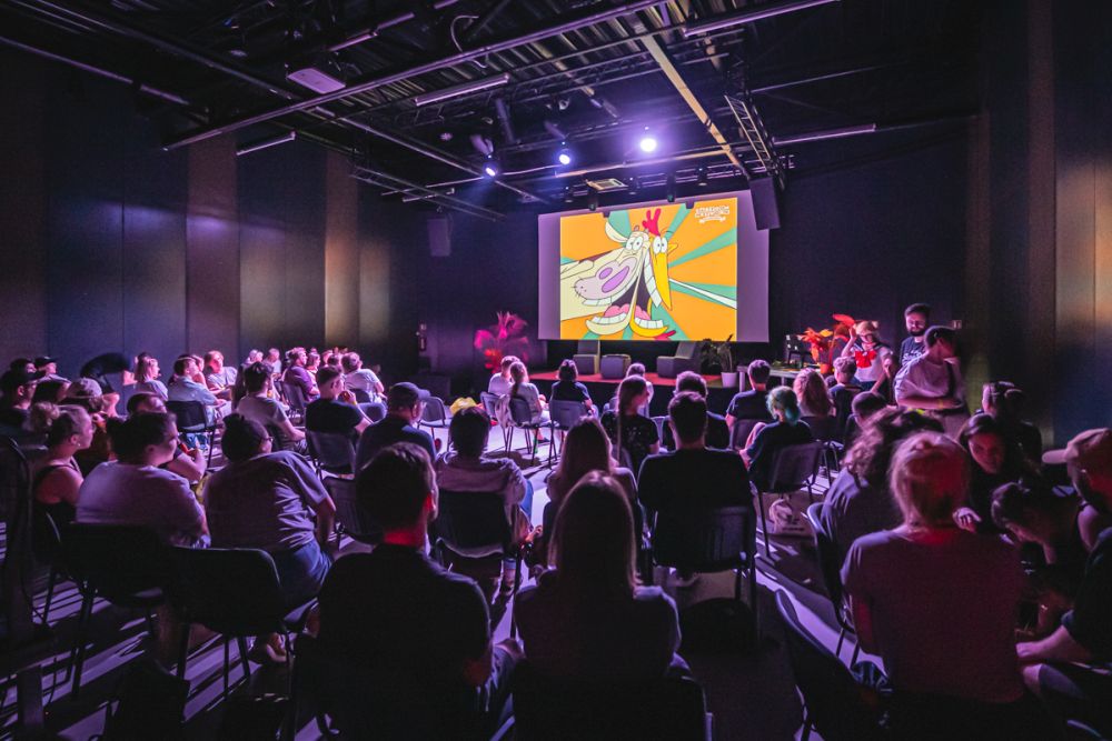 Ludzie oglądają film animowany z krową na dużym ekranie.