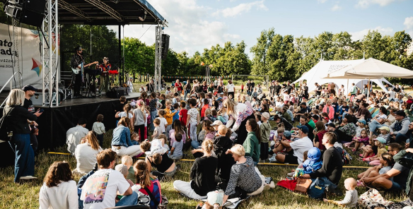 Ludzie siedzący przed sceną w parku