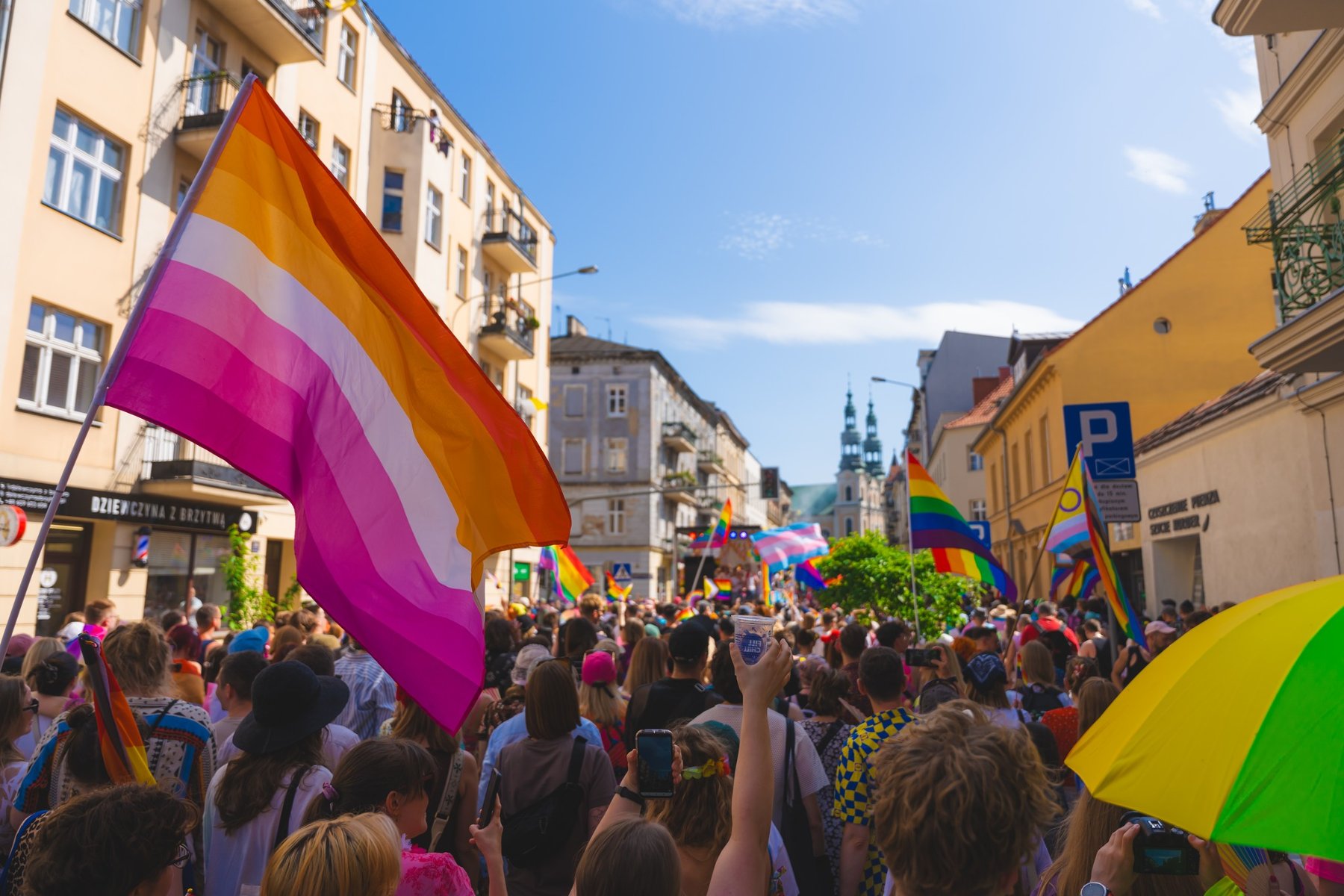 Marsz Równości. Tłum ludzi maszeruje powiewając tęczowymi flagami.
