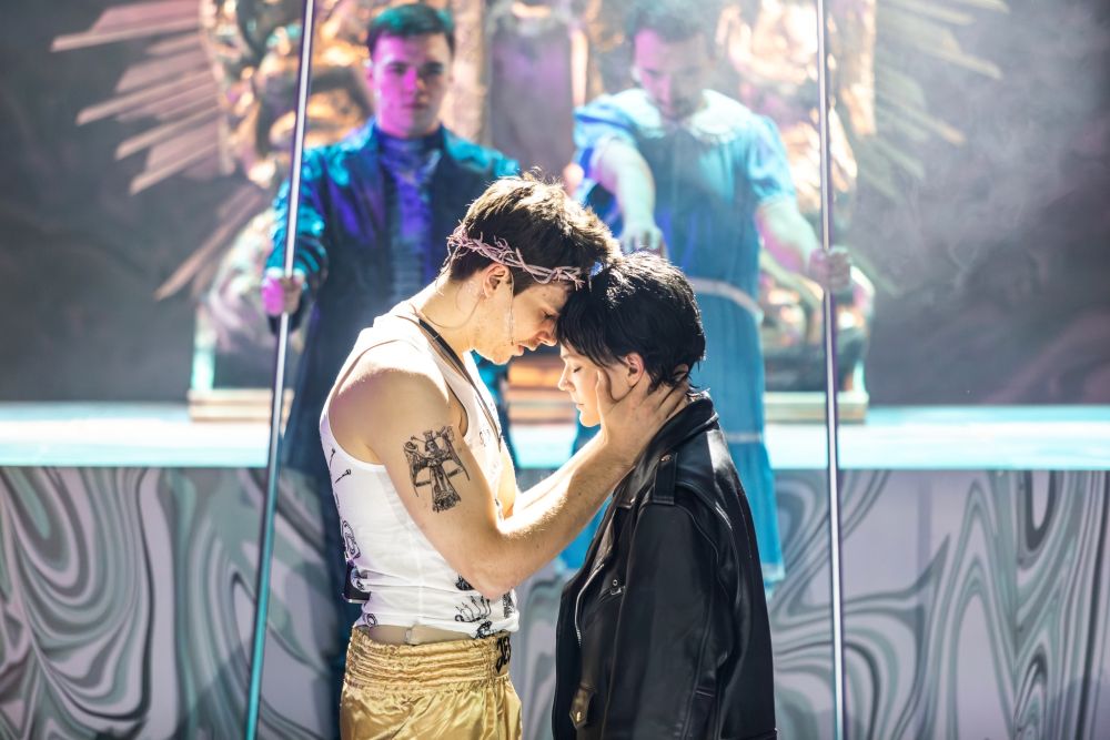 Mężczyzna w koronie cierniowej na głowie przytula dziewczynę w skórzanej kurtce.