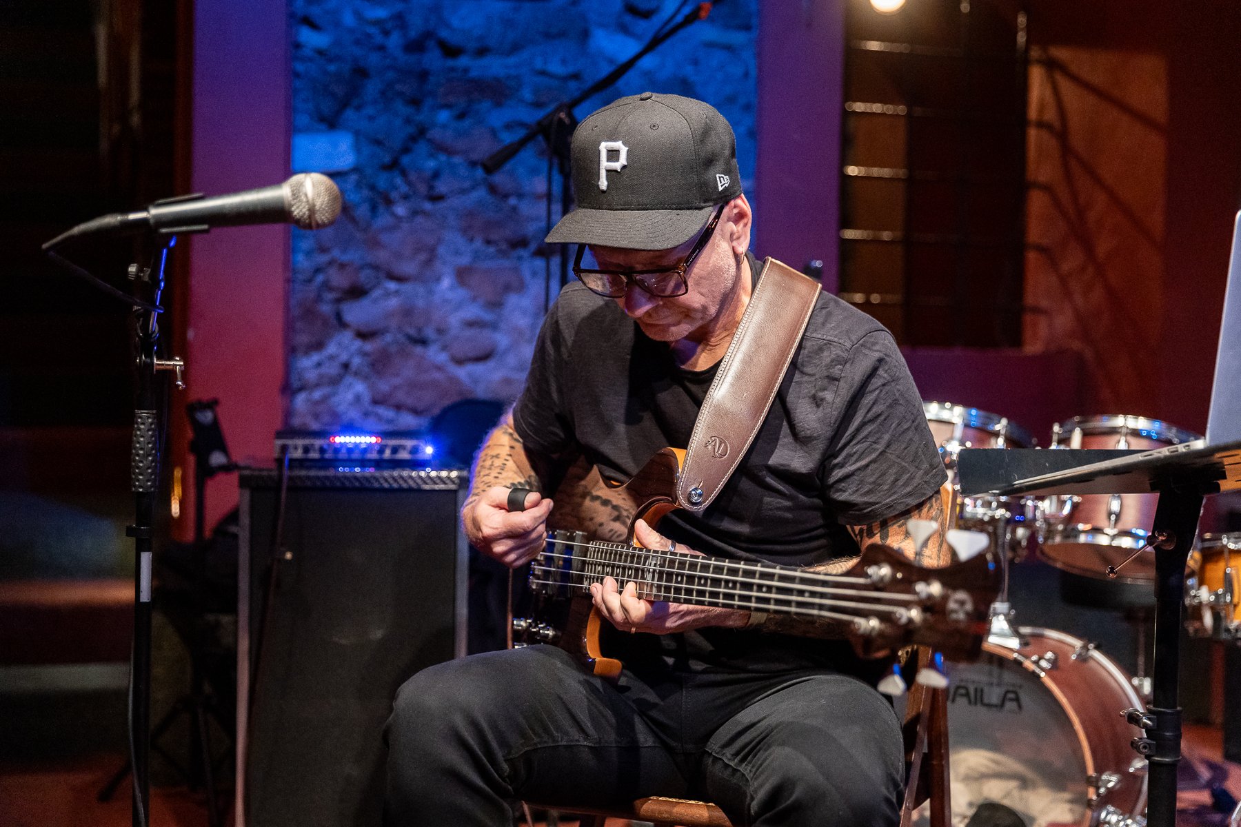 Mężczyzna w okularach pozuje z gitarą.