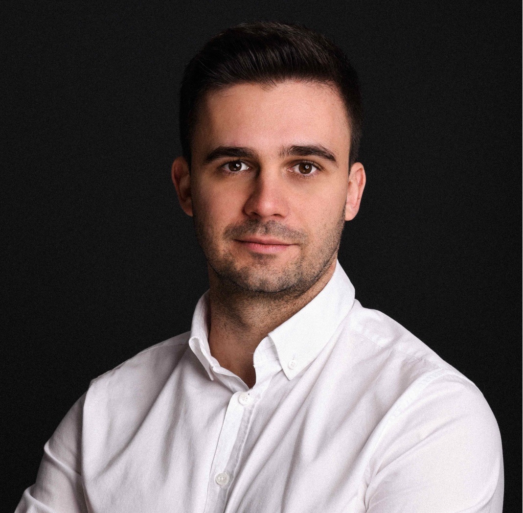 mężczyzna w wieku około 30 lat, ciemne, krótkie włosy, biała koszula