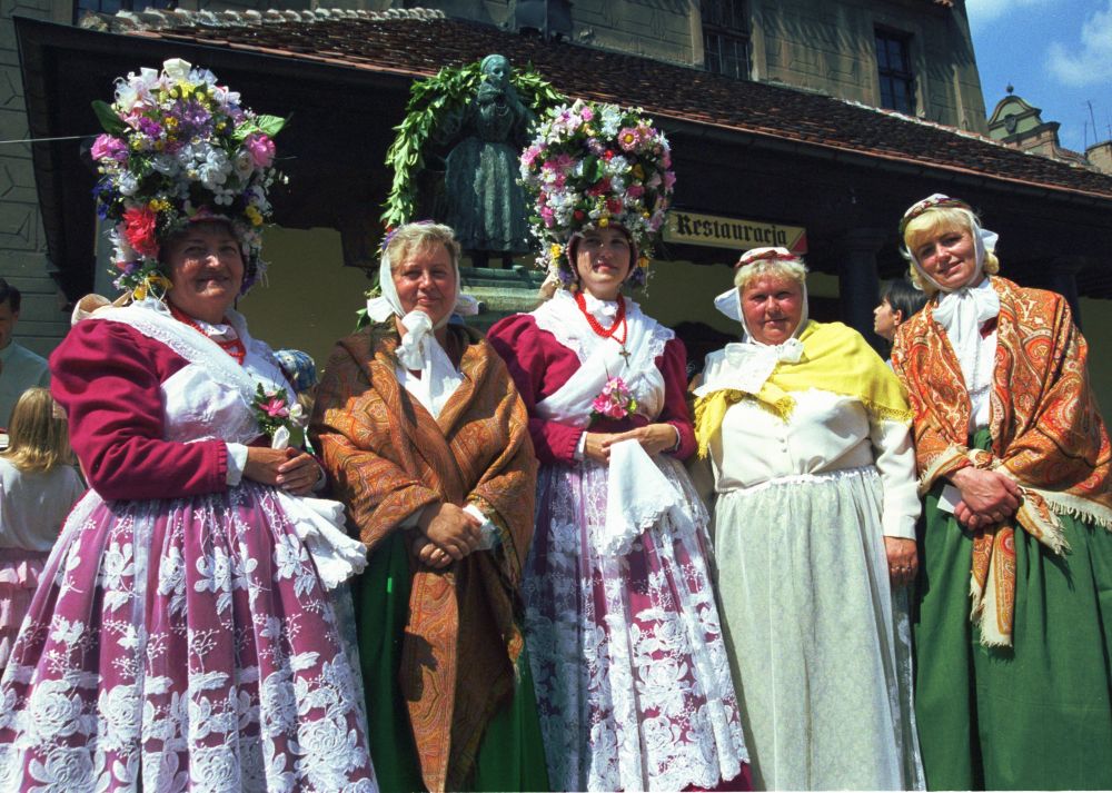 Młoda dziewczyna w bamberskim nakryciu głowy, dominują kwiaty białe, żółte, zielone.