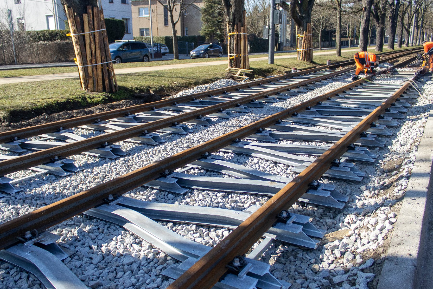 montaż nowych torów wzłuż al. Wielkopolskiej, w tle pas zieleni z zabezpieczonymi drzewami i chodnikiem
