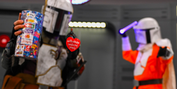 Na pierwszym planie widać czerwone serduszko WOŚP. W tle stoją dwie postaci w strojach z Gwiezdnych wojen