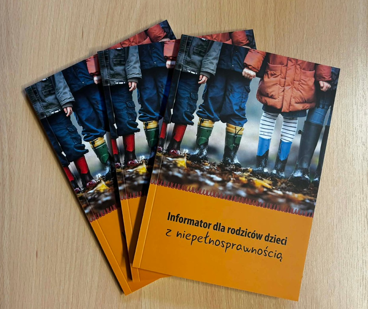 Na stole leżą trzy informatory dla rodziców dzieci z niepełnosprawnością