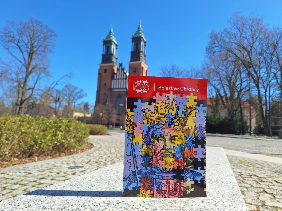 na tle katedry w Poznaniu - książka z wizerunkiem Bolesława Chrobrego w kolorowej grafice stylizowanej na puzzle