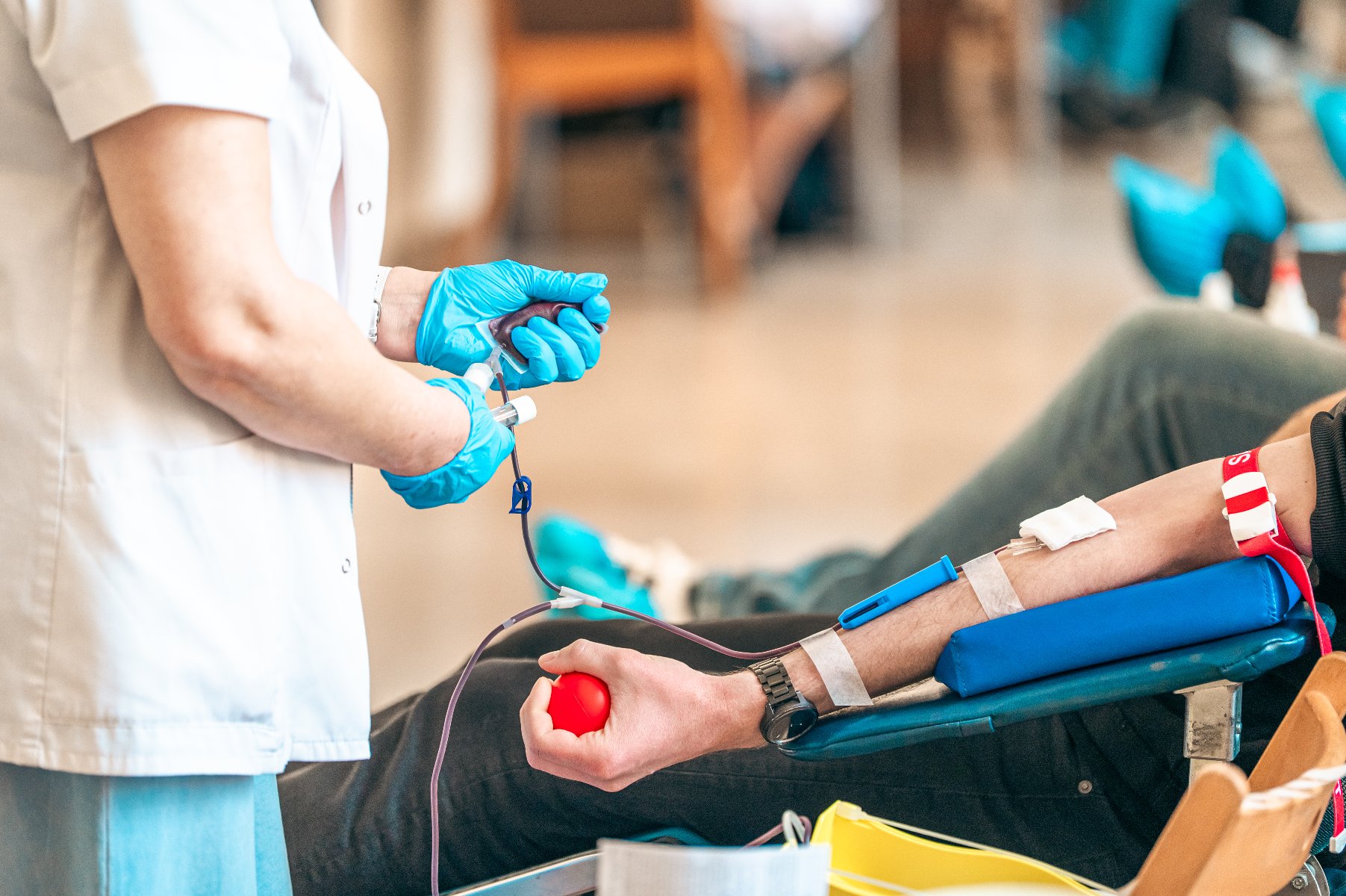 Na zdjeciu człowiek oddający krew, widać jego dłoń i ręce pielęgniarki