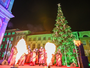 Na zdjęciu dużą choinka, przed nią ludzie, widać dwie duże pochodnie