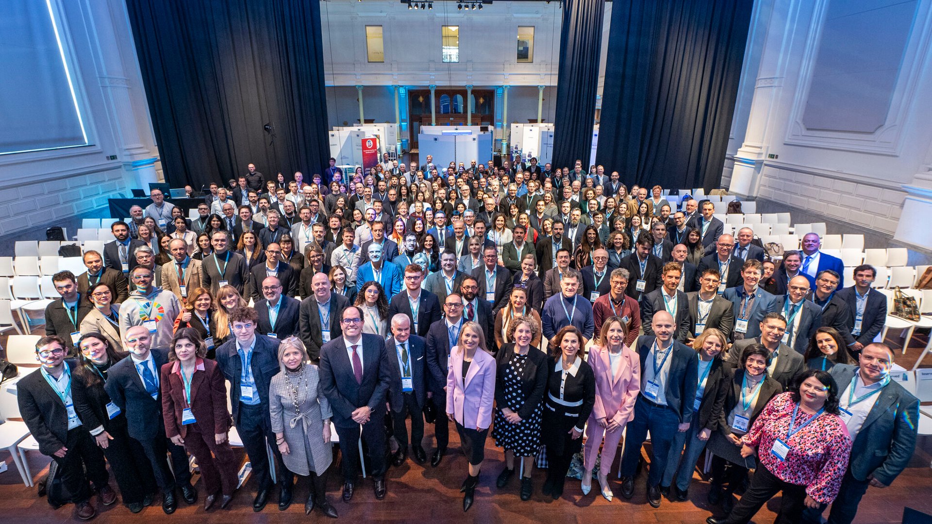 Na zdjęciu duża grupa ludzi w sali konferencyjnej pozujących do wspólnego zdjęcia