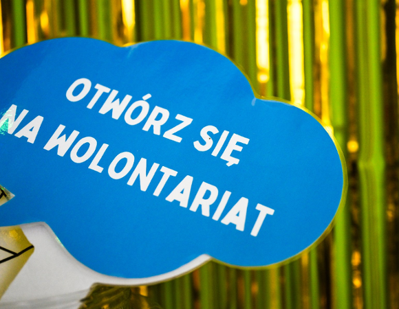 Na zdjęciu duży komiksowy "dymek" z napisem: otwórz się na wolontariat