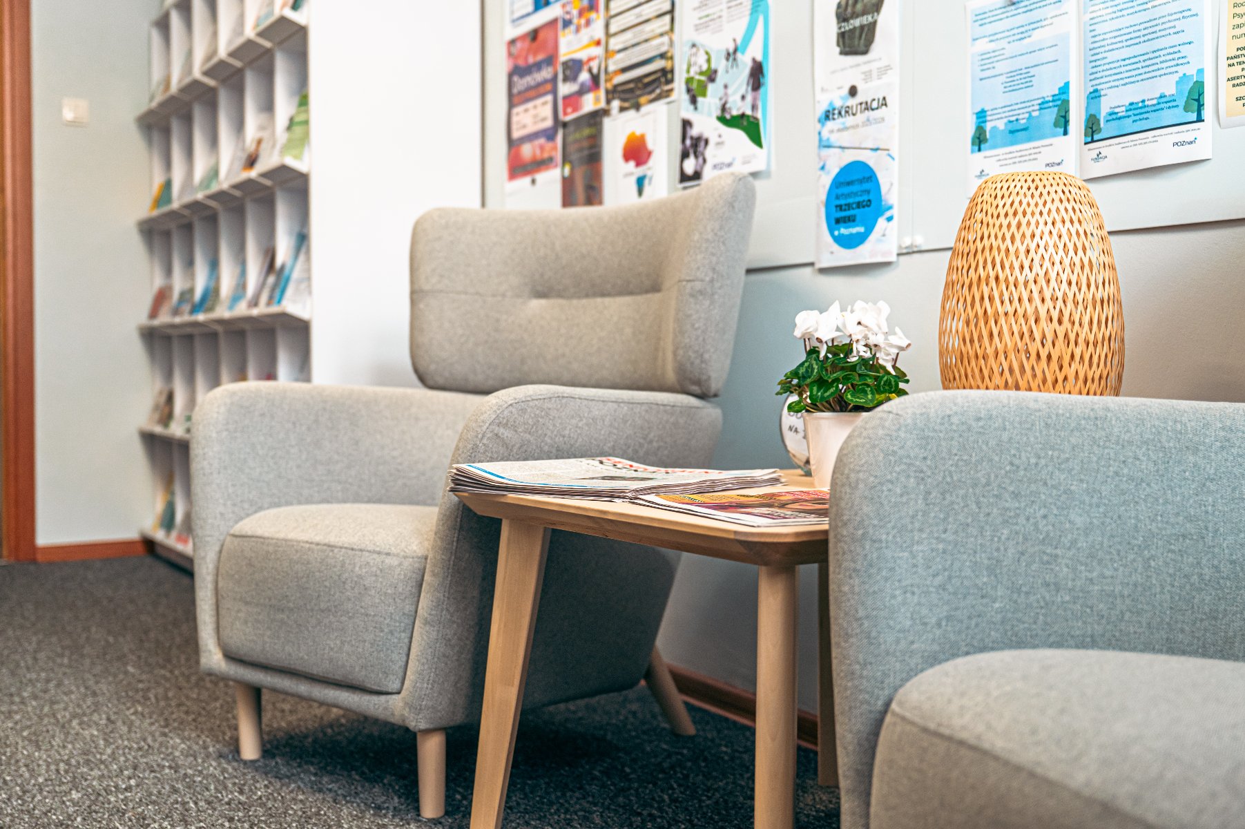 Na zdjęciu dwa fotele i stolik w przytulnym pomieszczeniu, w tle widać regał