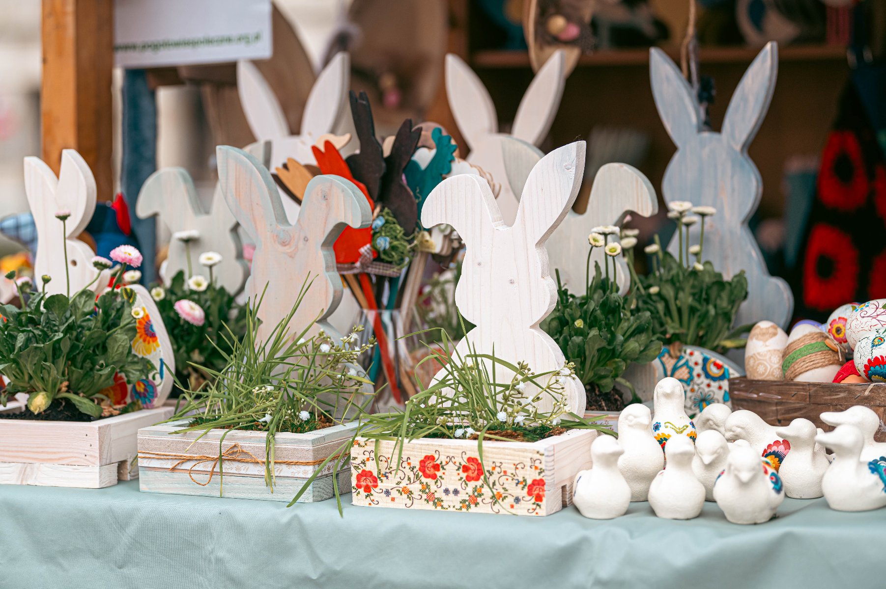 Na zdjęciu dwie ozdoby w kształcie kur, na pierwszym planie zastawa stołowa