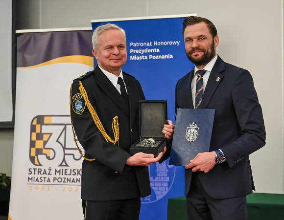 Na zdjęciu dwóch mężczyzn, jeden - w mundurze - trzyma Srebrną Pieczęć, drugi - teczkę z herbem Miasta