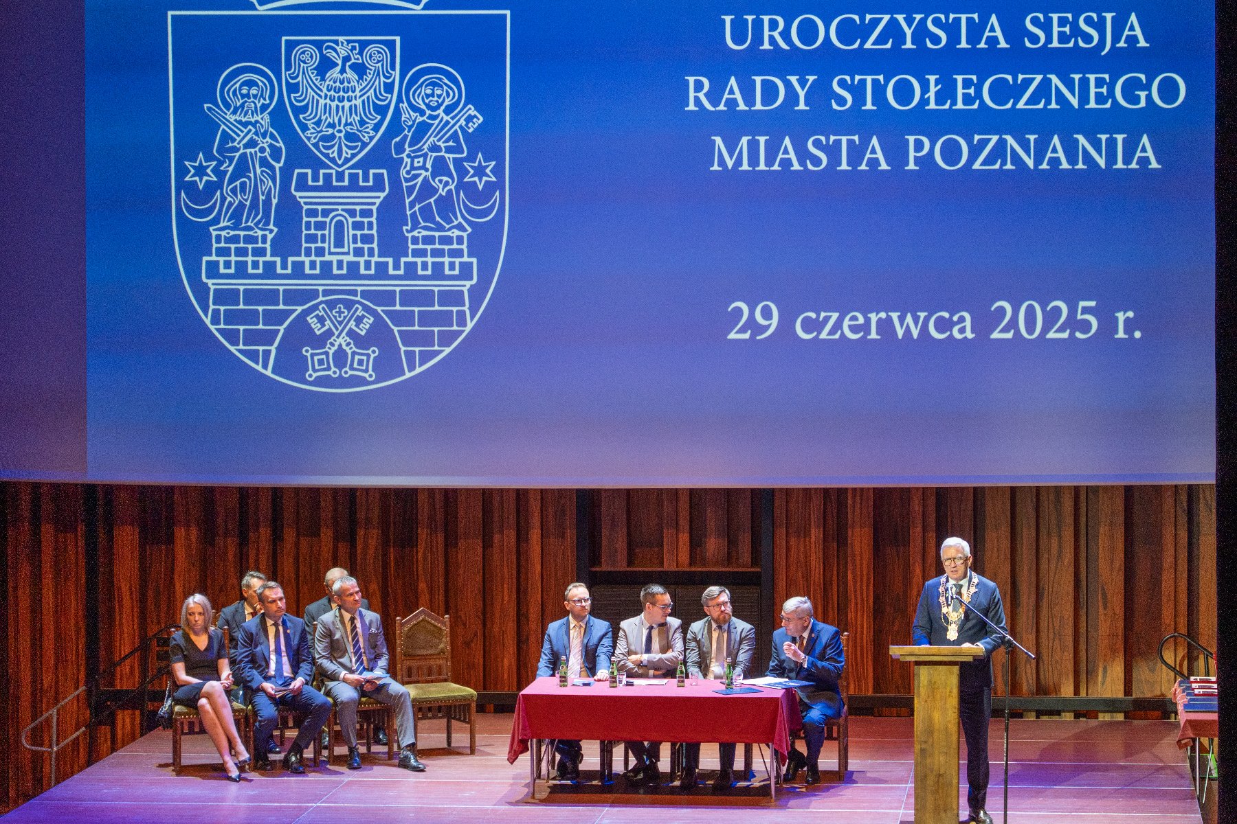 Na zdjeciu dwóch mężczyzn wręcza wyróznienie starszej pani