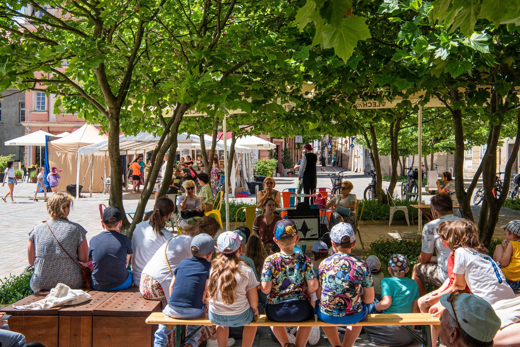 Na zdjęciu dzieci siedzące na placu Kolegiackim