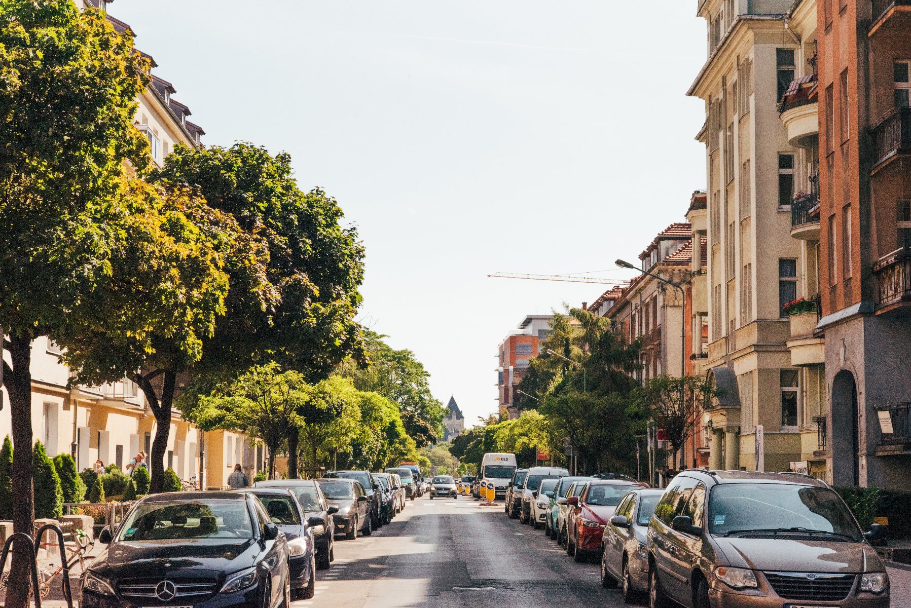Na zdjęciu jeżycka ulica, widać kamienice, drzewa i parkujące samochody