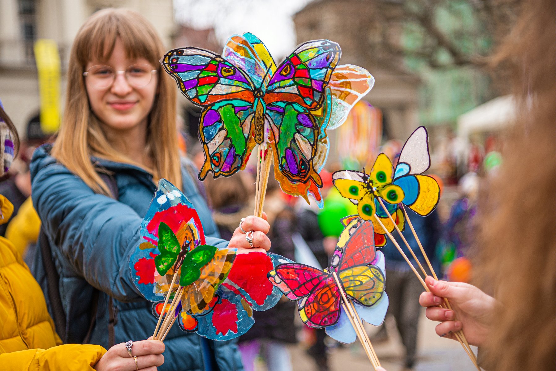 Na zdjęciu kobieta machająca kolorową girlandą z papieru