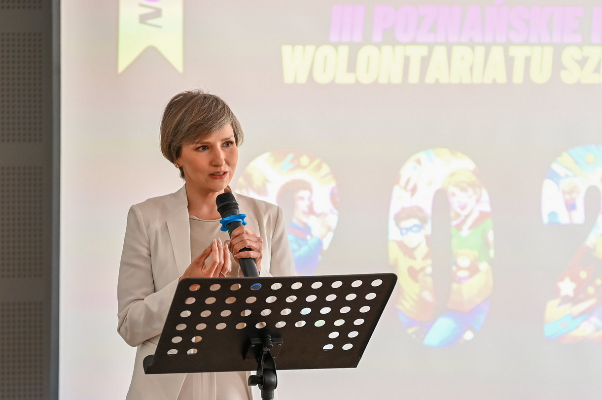 na zdjęciu kobieta stojąca przy mównicy z mikrofonem