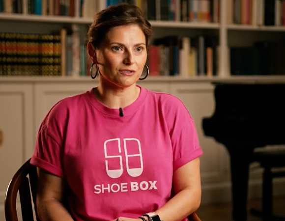 Na zdjęciu kobieta w koszulce z napisem: shoe box