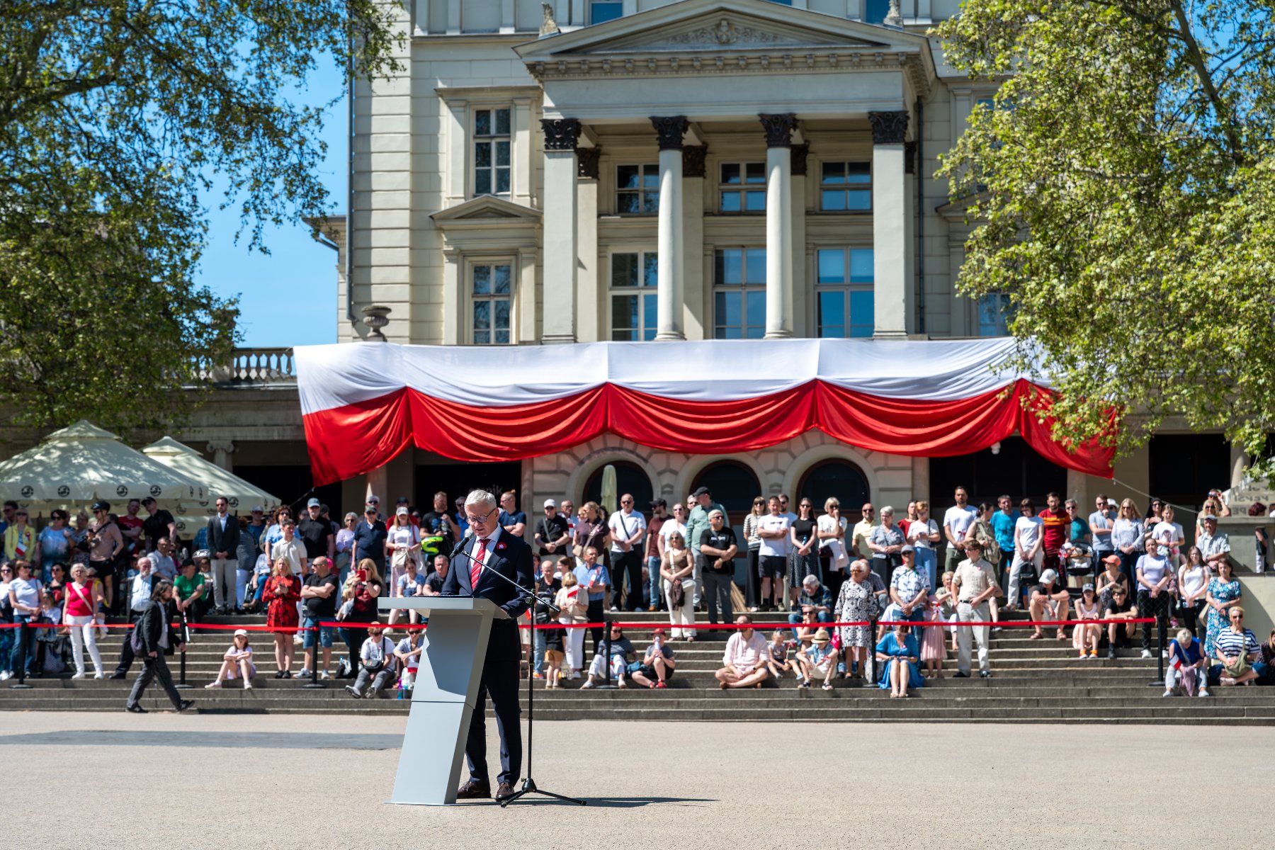 Na zdjęciu ludzie zgromadzeni na Placu Wolności, w tle budynek, na nim duża flaga Polski